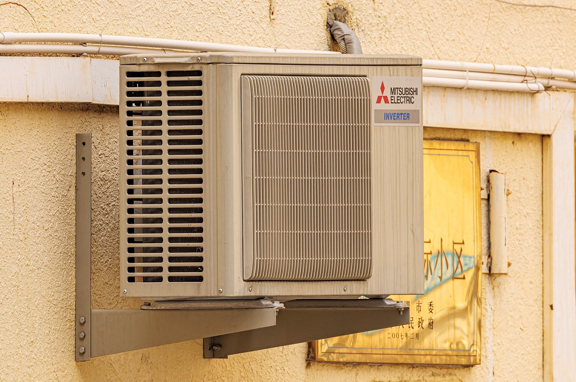 Mitsubishi Electric outdoor unit on a yellow wall